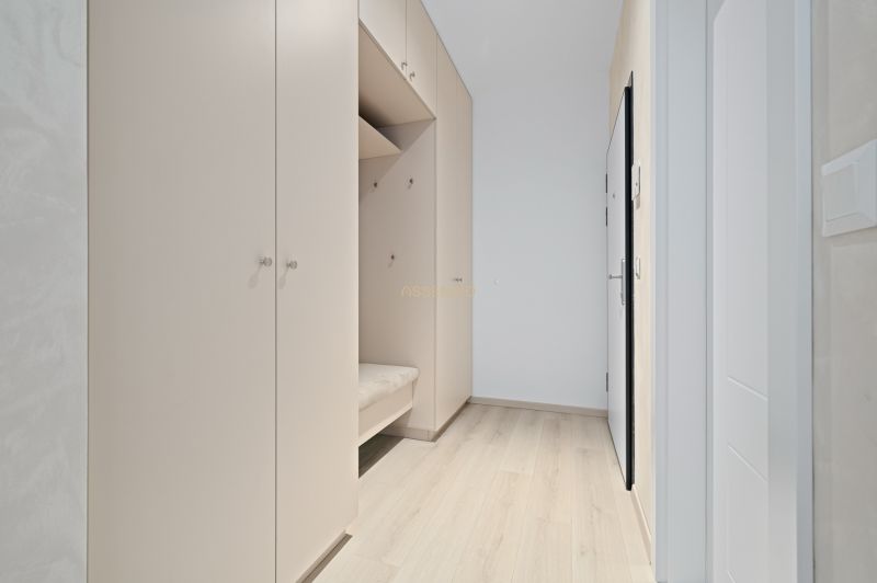 An entrance hall with a white wardrobe and a wooden decor floor in a 3-room apartment.