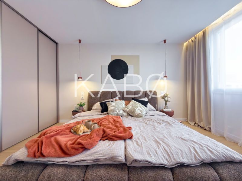 A bedroom in a three-room apartment with a bed, curtains, and a wardrobe; a floor with a wooden decor.