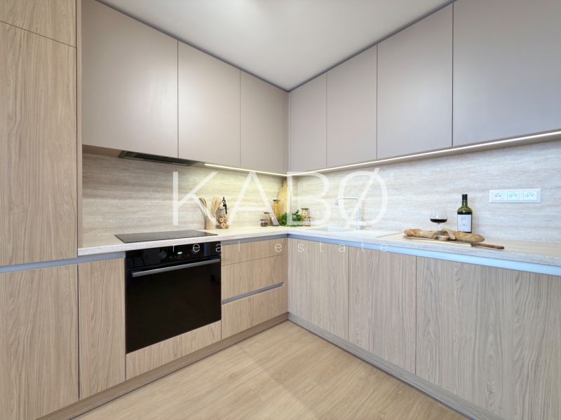 A kitchen in a 3-room apartment with a wooden decor floor and built-in appliances.