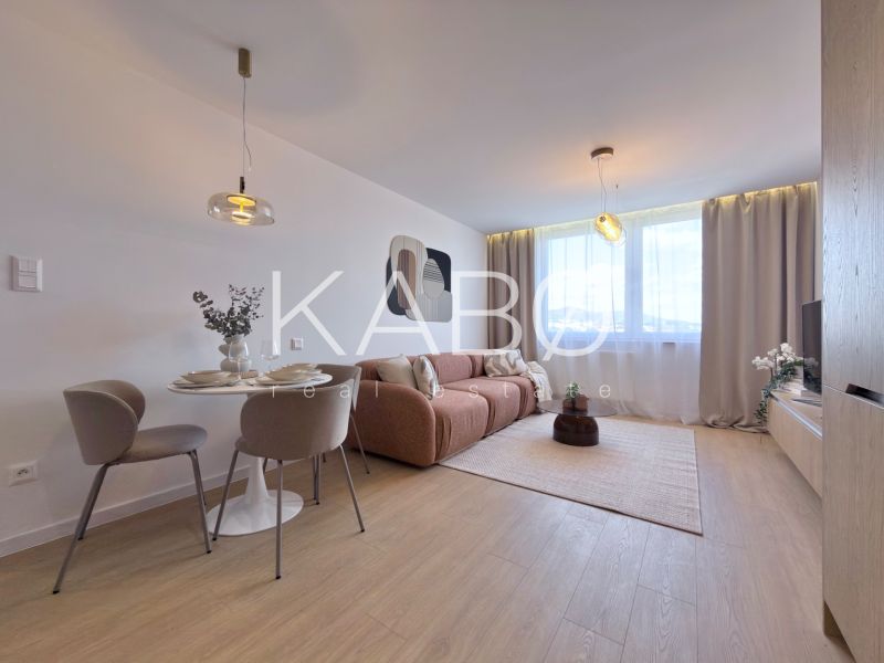 Living room with a sofa, dining table, and wood-patterned flooring in a three-room apartment.