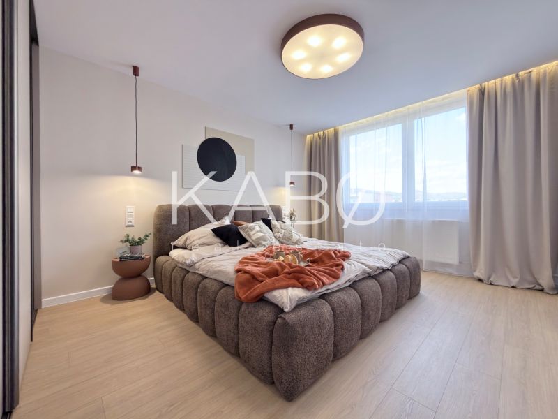 A bright bedroom with a large bed and a wooden decor floor in a 3-room apartment.