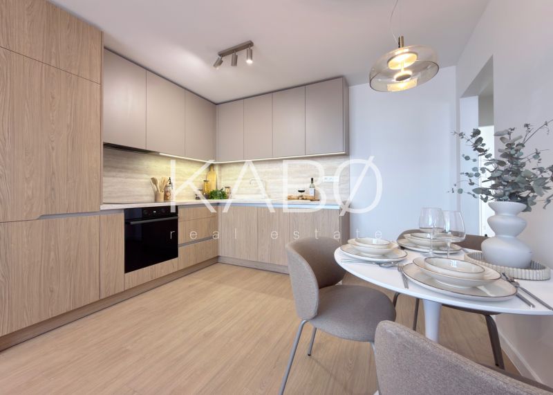 A kitchen with light cabinets and a wood-patterned floor in a three-room apartment.