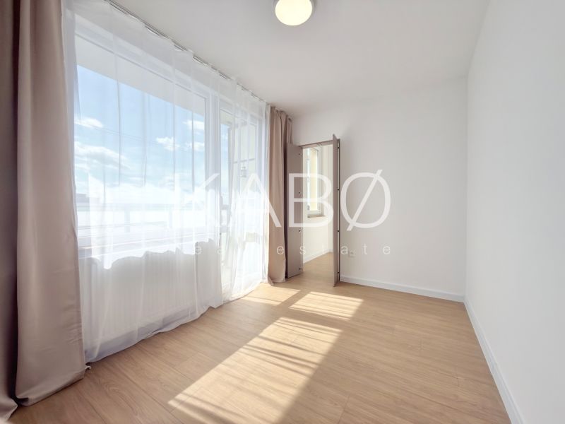 A bright room with curtains and a wooden decor floor in a 3-room apartment.