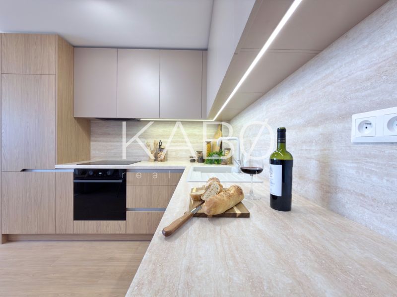 A kitchen in a 3-room apartment with wine, bread, and a wooden decor floor.