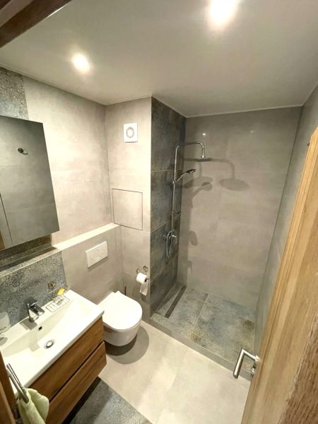 Compact bathroom in a studio apartment with an open shower and tiles.