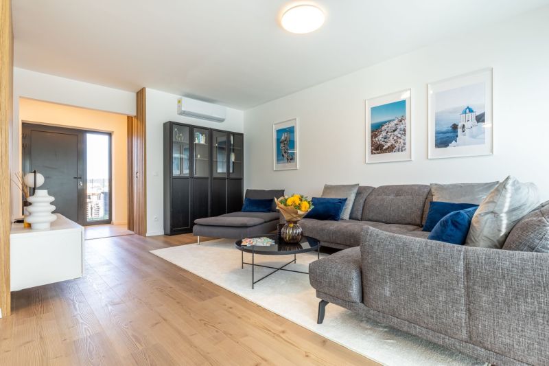 Living room in a family house with a wooden decor floor, a sofa, and decorative items.