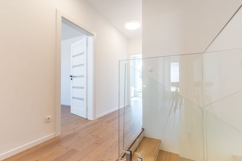Interior of a family house with a wooden decor floor and glass railing by the stairs.