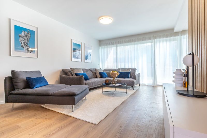 Living room in a family house with a sofa, paintings, and a wooden decor floor.