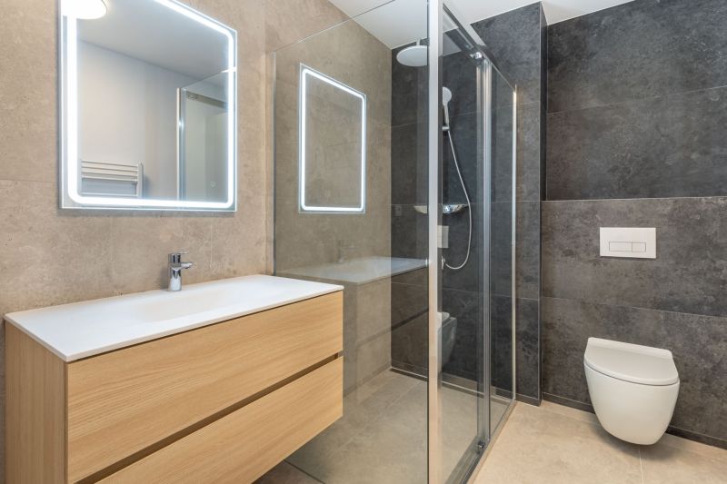 Bathroom with wooden furniture, a shower cabin, and a large mirror in a family house.