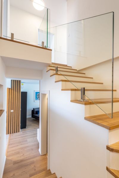 Interior of a family house with wooden stairs, glass railing, and flooring with a wooden decor.