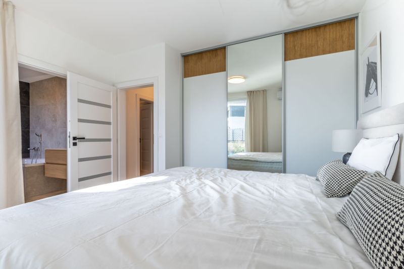 A bedroom in a family house with a large built-in wardrobe and a bed in light colors.