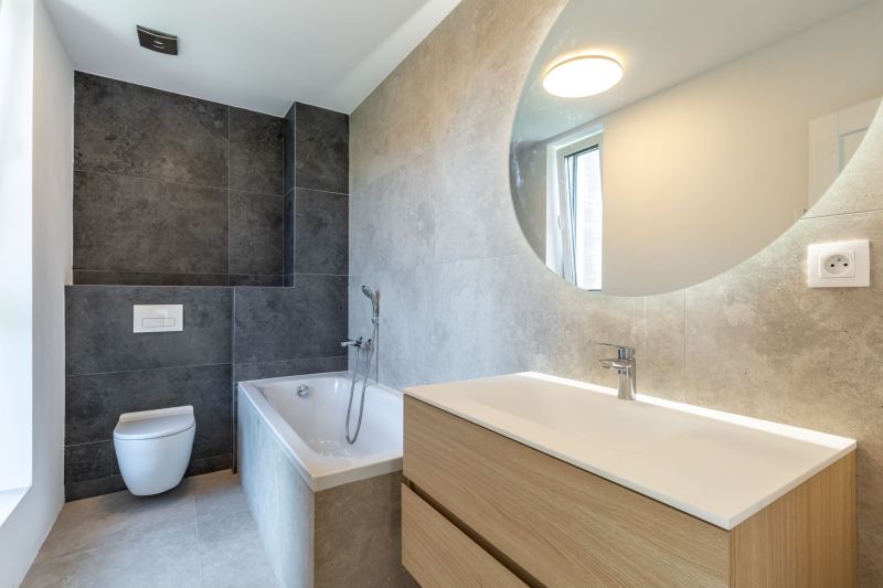 A bathroom in a family house with a bathtub, a sink, and tiles in dark tones.
