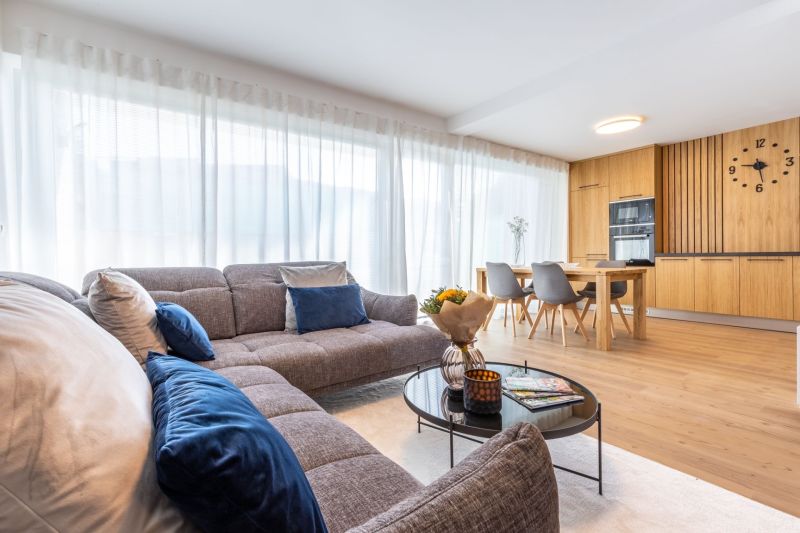 Living room in a family house with a sofa, dining table, and wooden decor flooring.