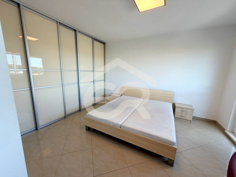 Bright bedroom with a sliding wardrobe, bed, and tiled floor in a studio apartment.