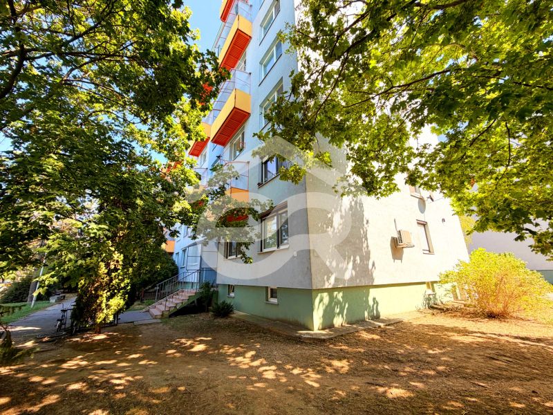An apartment building with colorful balconies on Lúky Street in Vráble, surrounded by trees.
