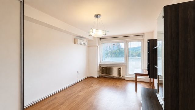 Living room with wood-patterned flooring, air conditioning, and a large window in a 3-room apartment.