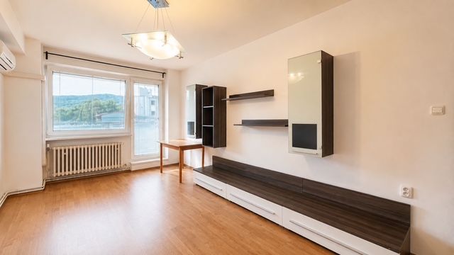 A room in a 3-room apartment with a wooden decor floor and built-in shelves.