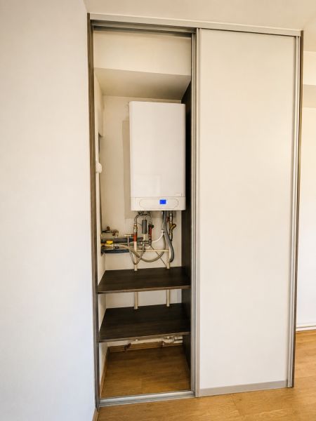 Built-in wardrobe with a boiler in a 3-room apartment, floor with wood decor.