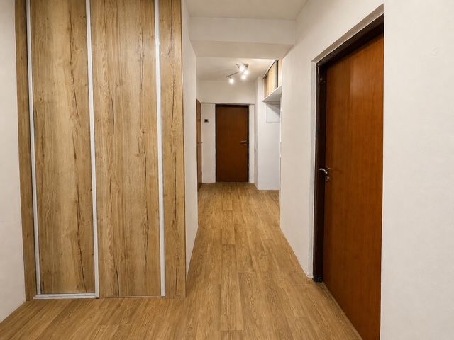 A hallway in a 3-room apartment with a wood-patterned floor and built-in wardrobes.