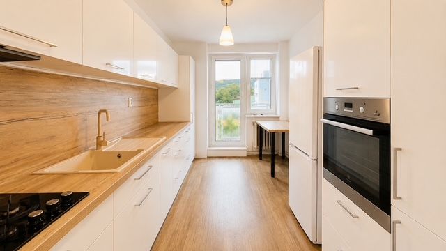 A kitchen in a 3-room apartment with a wooden decor floor, white cabinets, and a stove.