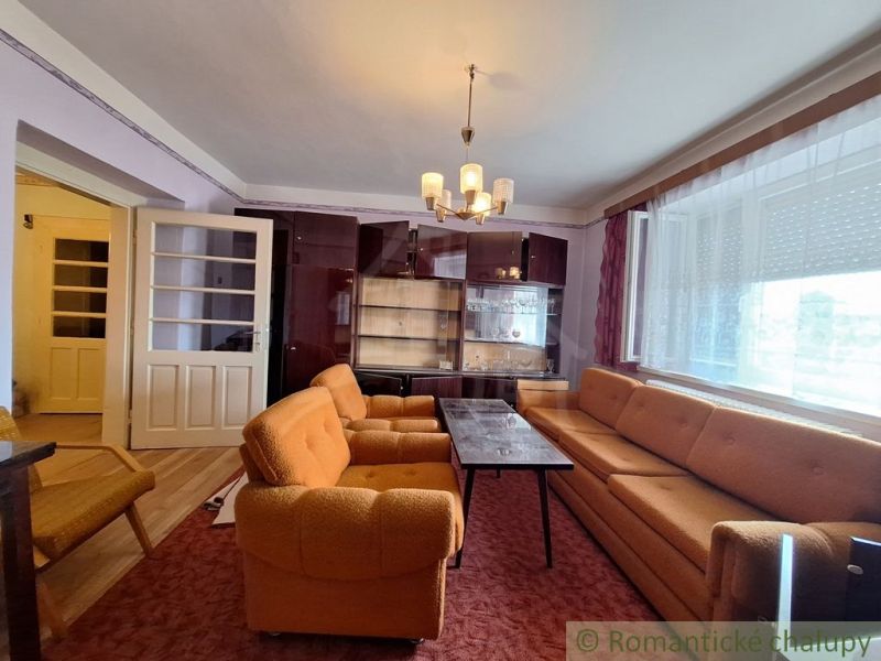 Living room in a family house with orange furniture and a display cabinet.
