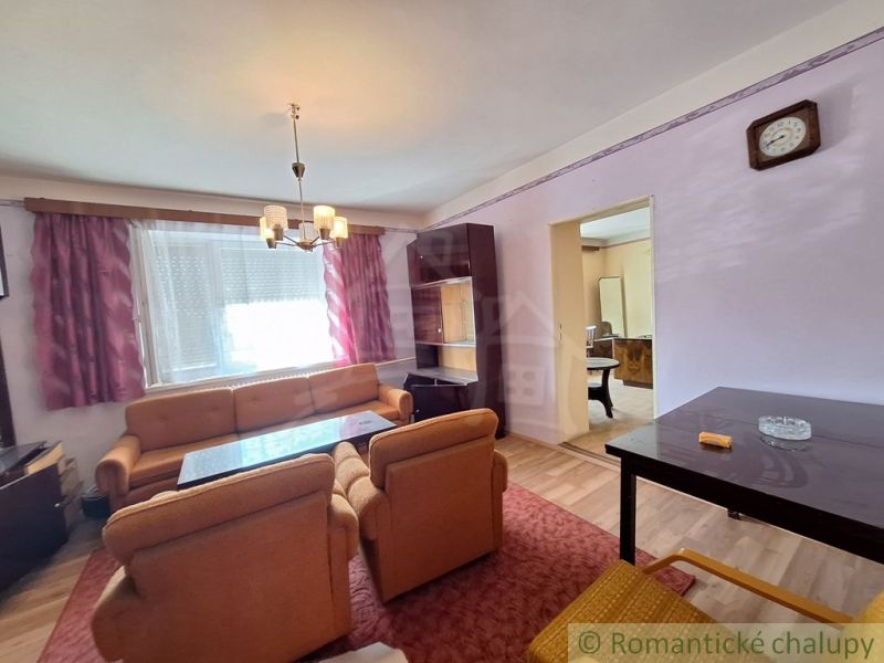 Living room of a family house with an orange sofa set and a cabinet ensemble.