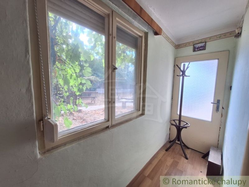 A narrow hallway in a family house with a window, a coat rack, and a wooden decor floor.