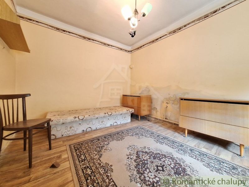 A room with a bed, a chair, and carpets, a floor with a wooden decor, corner furniture.