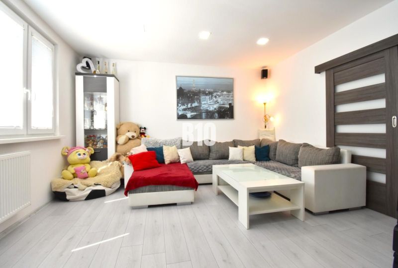 Living room in a 3-room apartment with a sofa, decorative pillows, and a wooden-patterned floor.