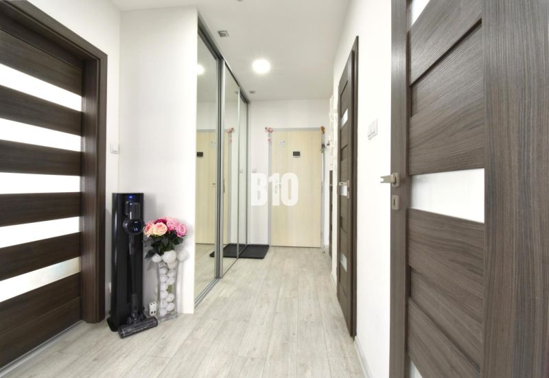 A hallway with a mirrored wardrobe and a wooden decor floor in a 3-room apartment.