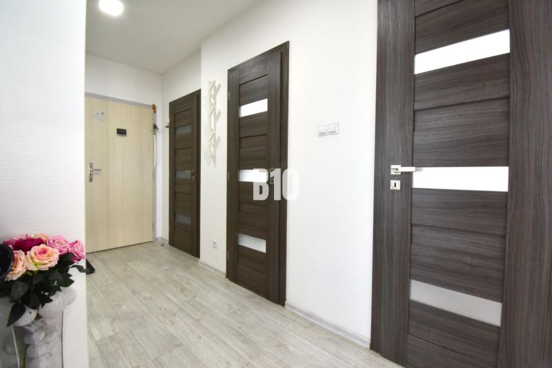 A hallway with doors and a floor with a wooden decor in a 3-room apartment.