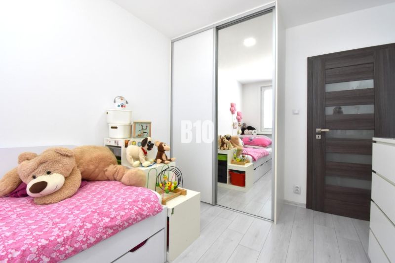 A children's room in a three-room apartment with a bed, plush toys, and a floor with a wooden decor.