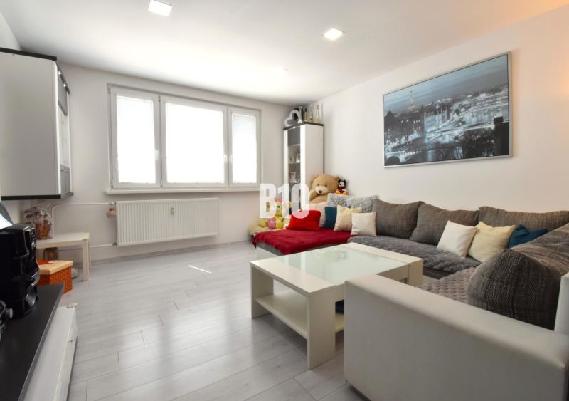 Living room in a three-room apartment with a wooden decor floor and a large sofa.