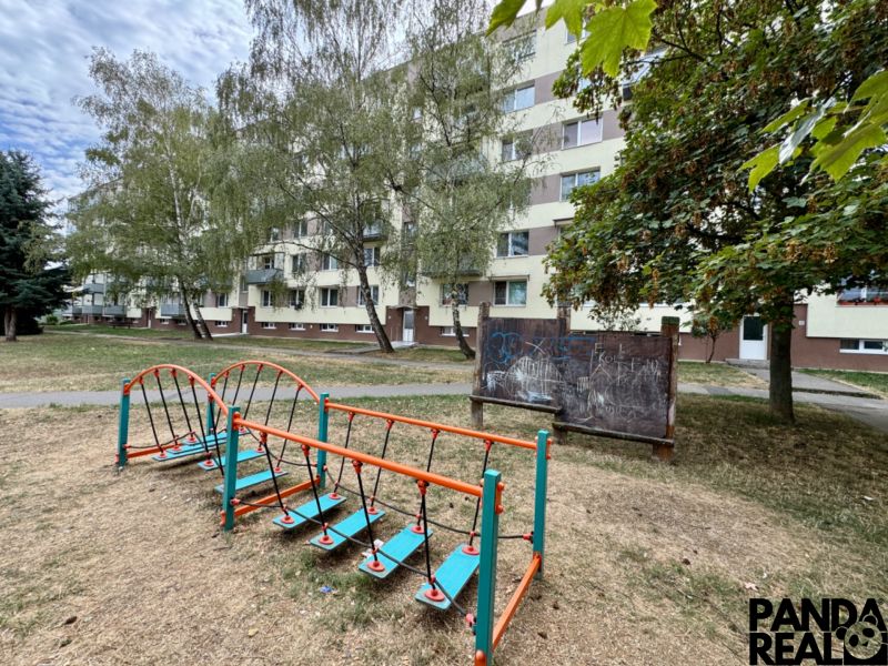 The exterior of the apartment building in Topoľčany with a children's playground and vegetation around the 1-bedroom apartment.