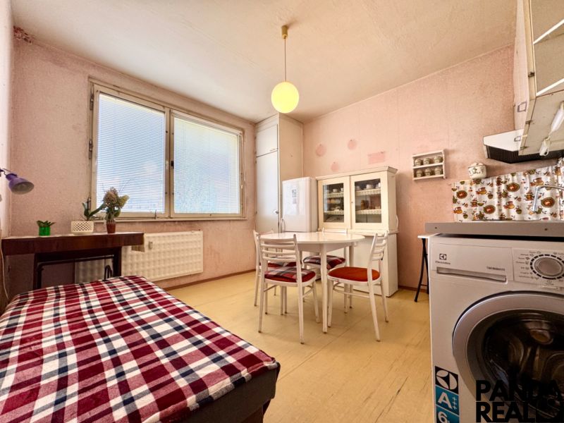A kitchen in a studio apartment with a table, chairs, a refrigerator, and decorative elements.