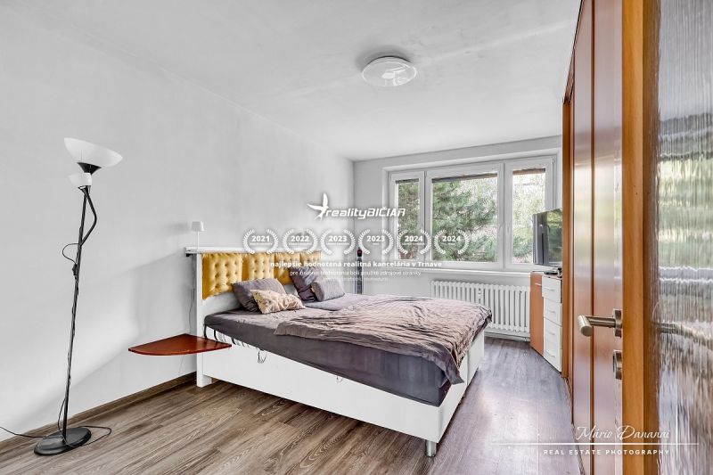 Bedroom with a bed and wooden decor flooring in a two-room apartment.