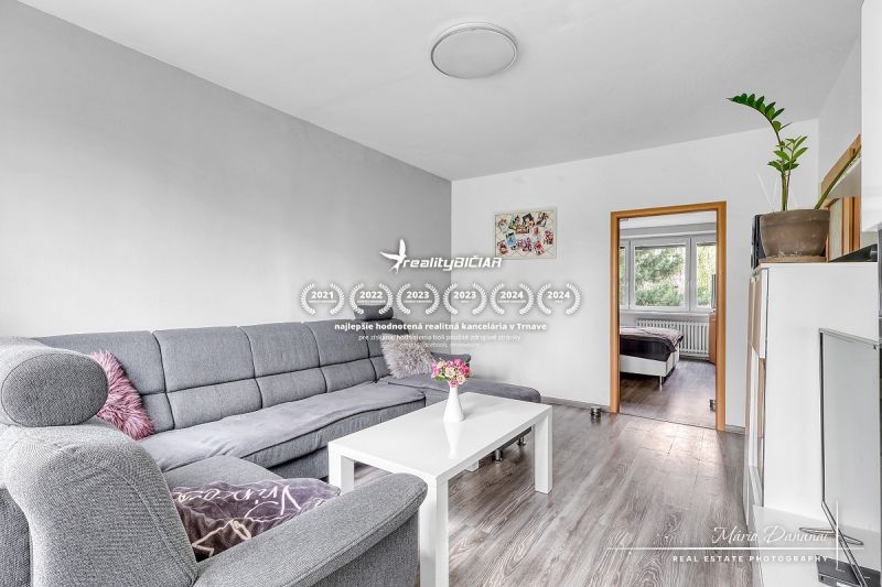 Living room with a corner sofa and a wooden decor floor in a 2-room apartment.