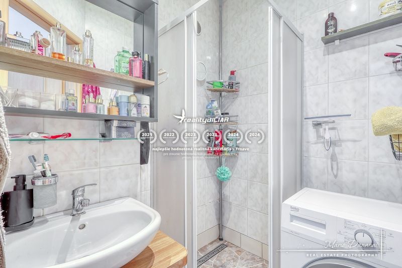 Bathroom in a 2-room apartment with a shower, sink, and washing machine.