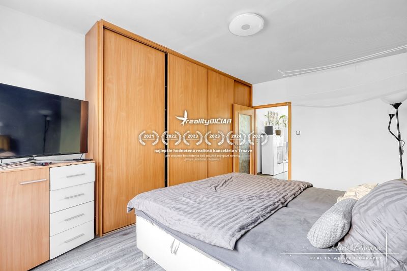 A bedroom in a two-room apartment with a wooden decor floor and a built-in wardrobe.