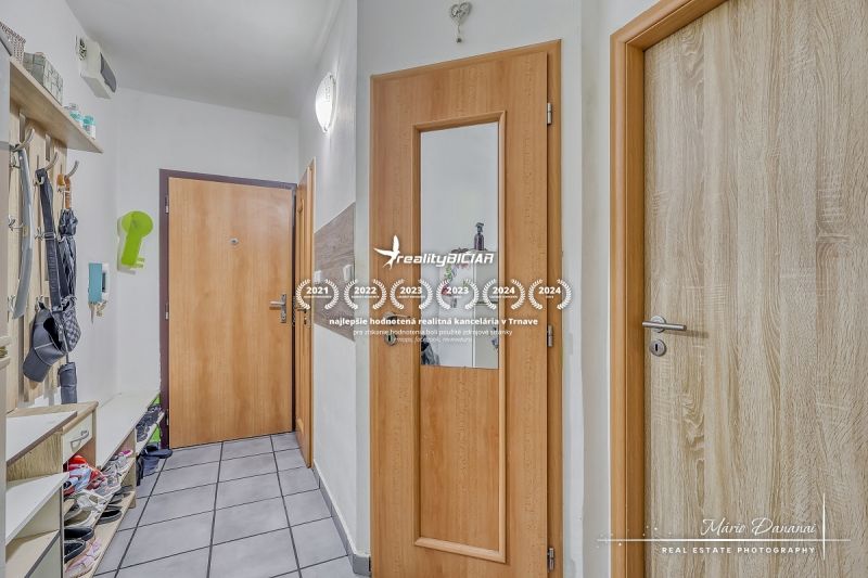 Hallway in a 2-room apartment with a tiled floor and wooden doors.