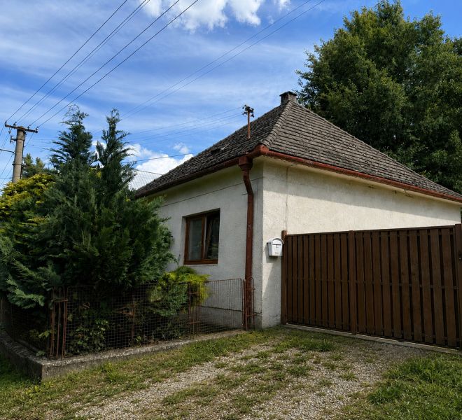 A family house in Urmince on Klačany Street, surrounded by trees and a fence.