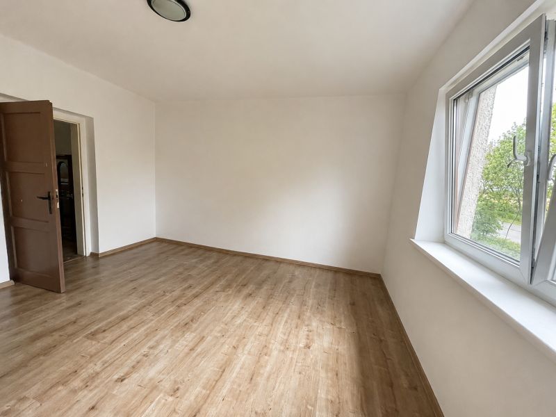 A room in a family house with a wooden decor floor and a large window.