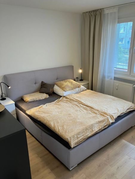 A bedroom with a large bed, nightstands, and a wooden decor floor in a 3-room apartment.
