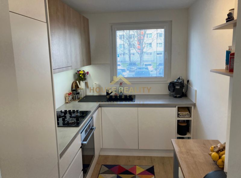 A kitchen in a 3-room apartment with a wood-patterned floor and a large window.