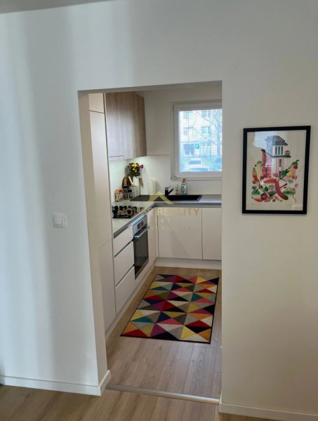 A small kitchen with a colorful rug and a wooden decor floor in a 3-room apartment.