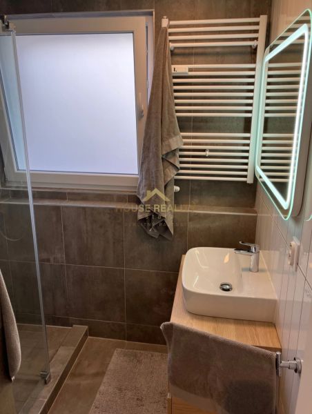 A bathroom in a 3-room apartment with a sink, shower, and ladder heating.