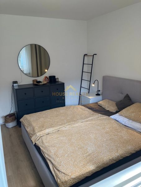 A bedroom with a bed, a dresser, and a round mirror in a 3-room apartment.