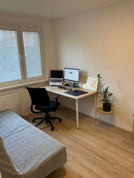 A workspace in a 3-room apartment with a wooden decor floor and a sofa bed.