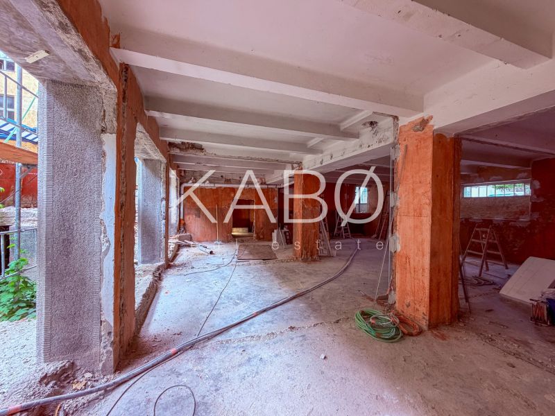 Commercial spaces under construction with exposed walls and columns, raw concrete surface.