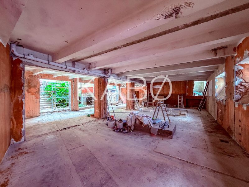 Under-construction commercial spaces with concrete flooring, ladders, and building materials.